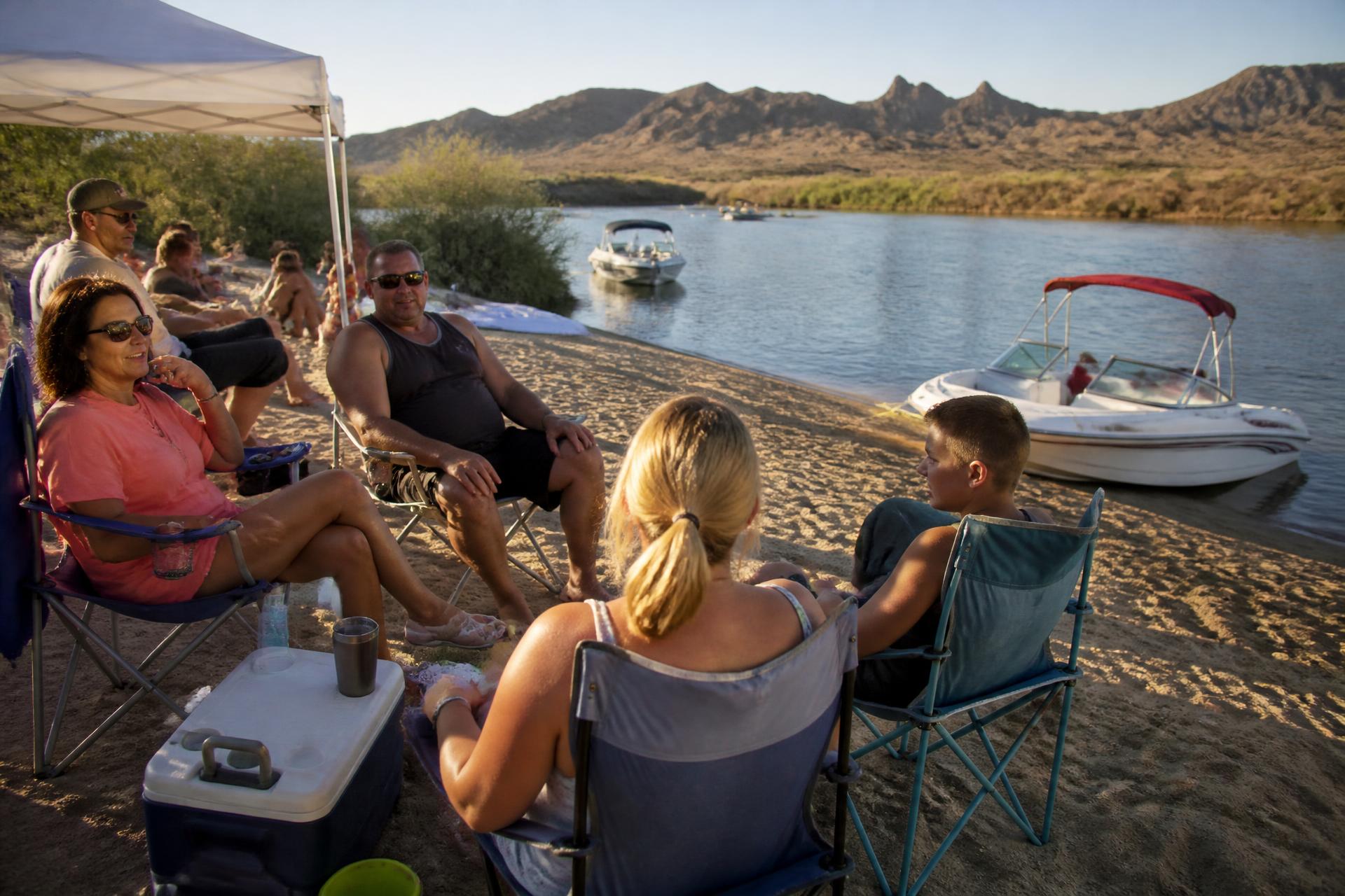 Family relaxing with chairs and a cooler on a Colorado River beach